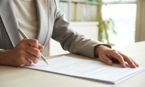 Hands of business entrepreneur signing document on her table